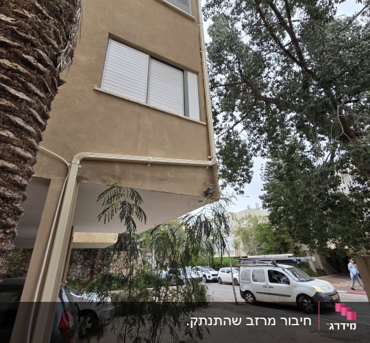 בניין עם צינורות חיצוניים ועצים ברחוב
